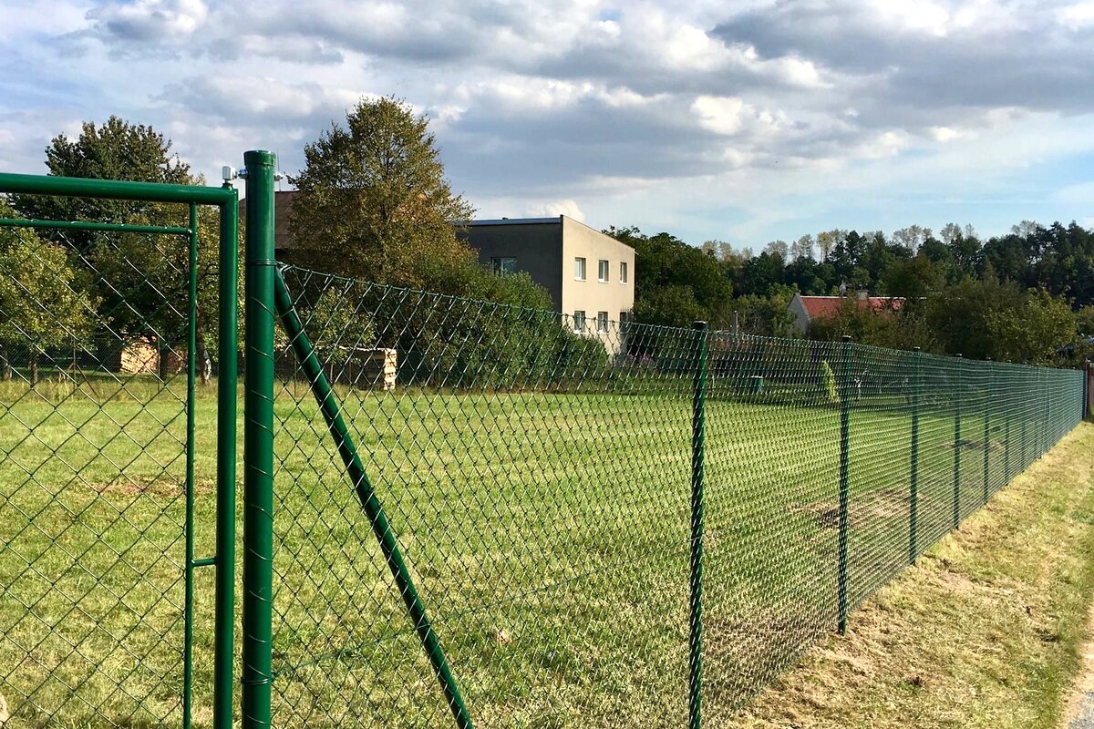 Zelený pletivový plot s brankou u pozemku — realizace Stavíme ploty